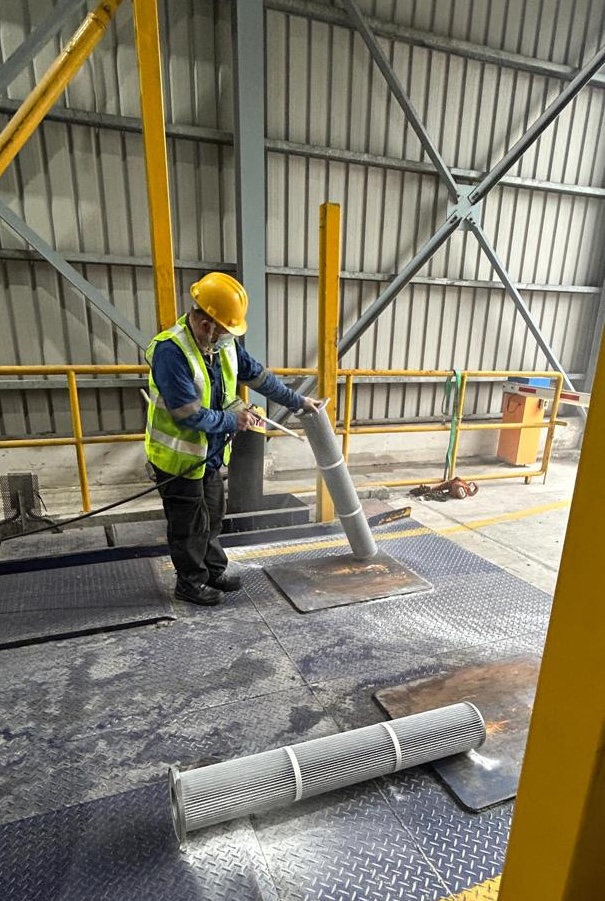 Technician maintaining dust collector filters in a material handling plant as part of turnkey system services by Mactex.